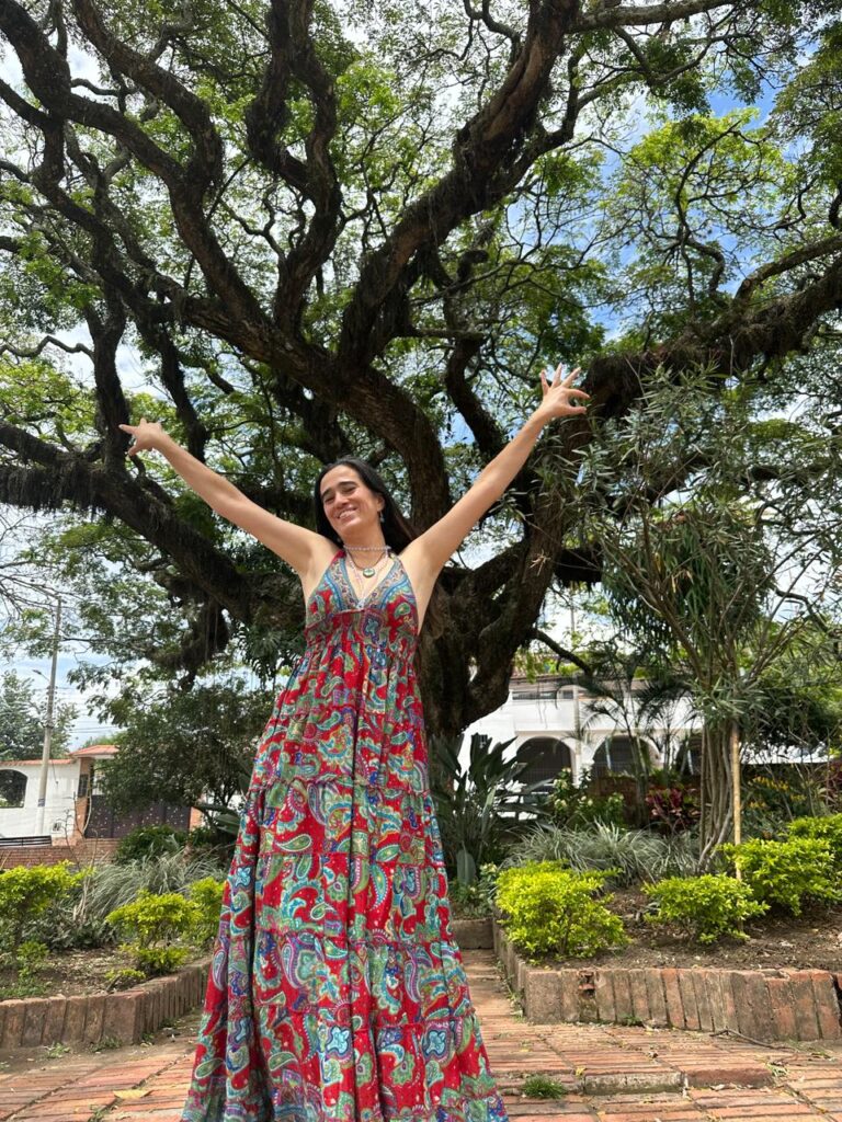 Cata Heincke en conexión con la naturaleza, abriendo los brazos en un camino de transformación consciente y expansión personal.