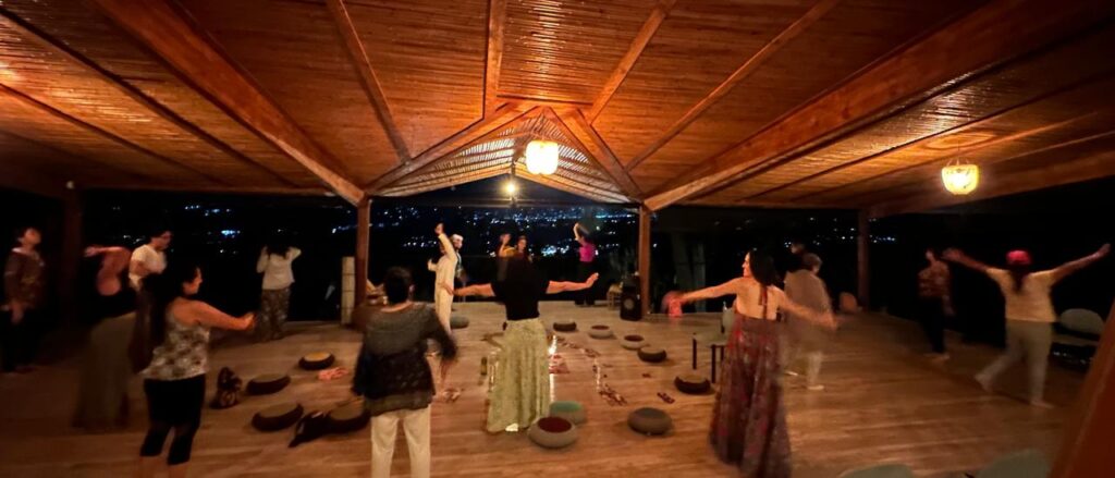 Grupo en danza ritual nocturna guiada por Cata Heincke, conectando con su luz interior en un espacio abierto.