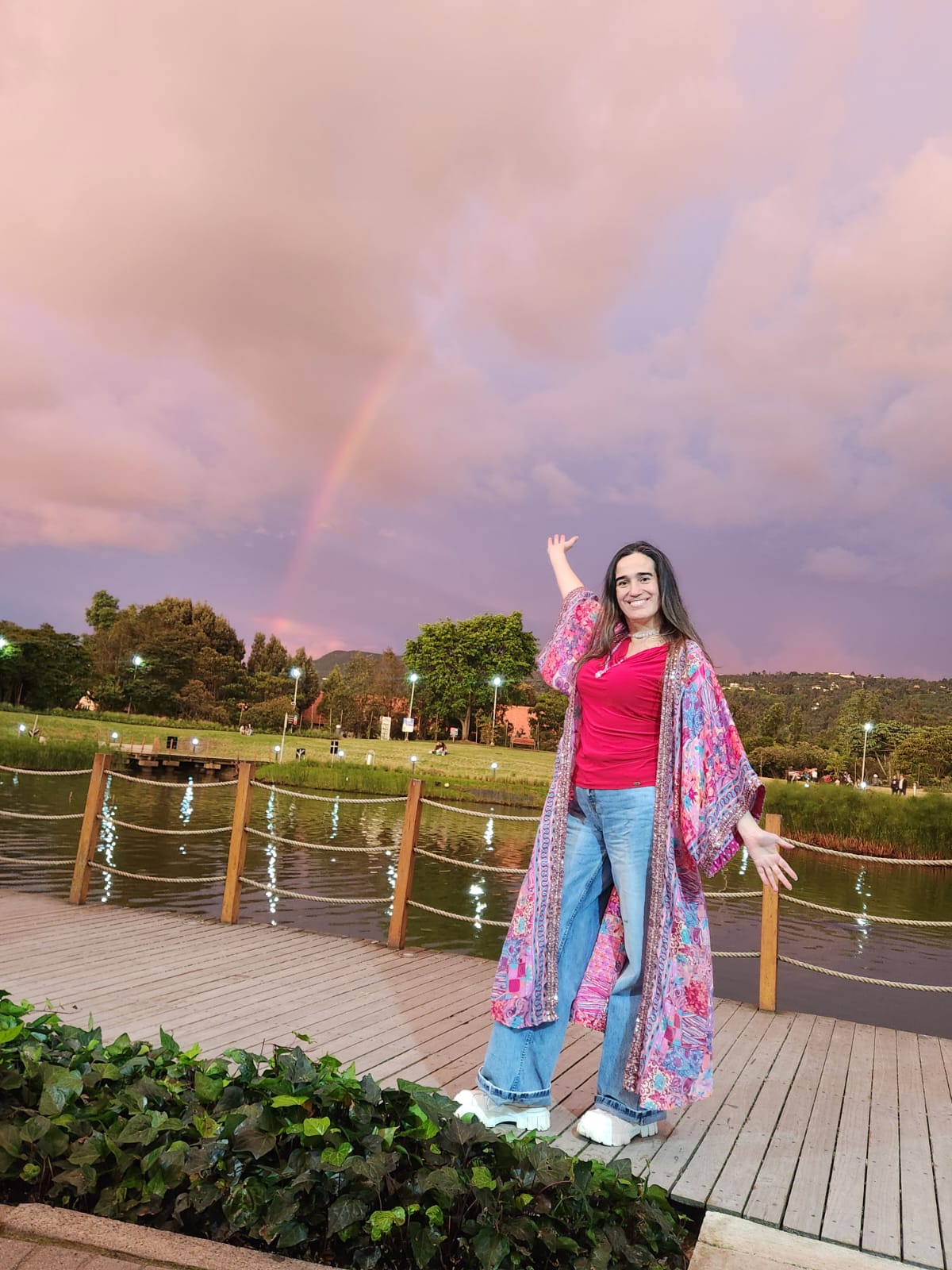Cata Heincke sonriendo bajo un arcoíris al atardecer, simbolizando el inicio de un nuevo camino y la expansión del alma.