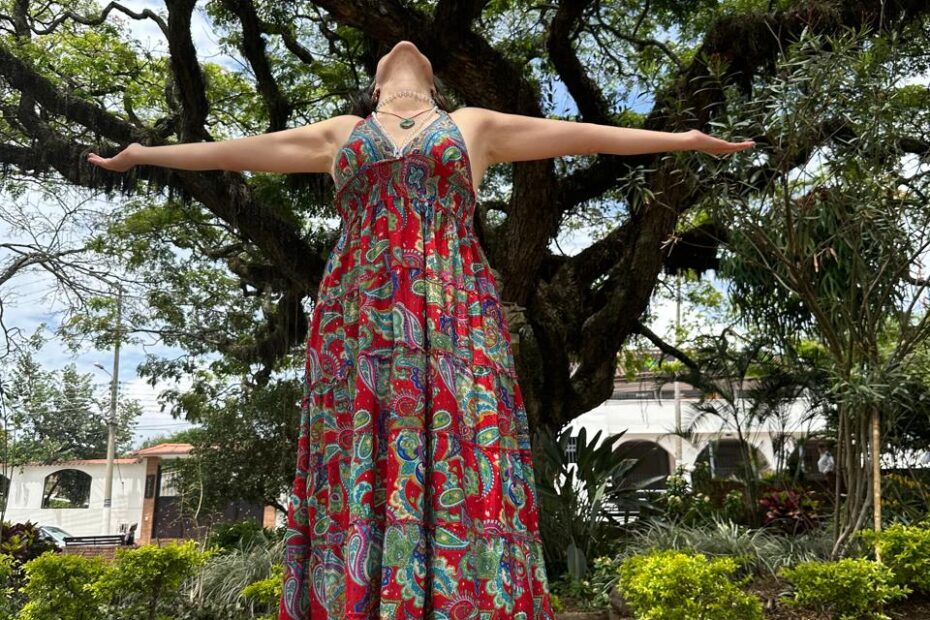 Cata Heincke de brazos abiertos bajo un gran árbol, simbolizando el renacimiento interior y la expansión consciente en la Rueda del Fénix.