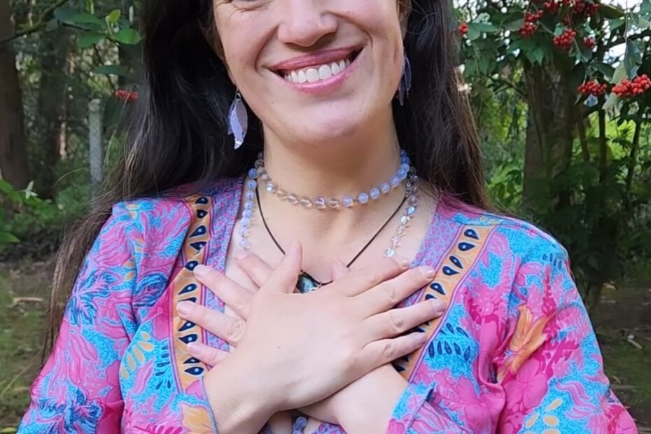 Cata Heincke sonriendo con las manos sobre el corazón, en un entorno natural, reflejando autenticidad y gratitud en su camino espiritual.